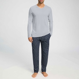 Model wearing Hanro Pyjamas Set in Celestial Night; grey long-sleeve top with navy geometric-print trousers