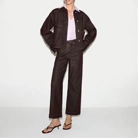 Model wearing Jigsaw burgundy coated denim jacket and matching wide-leg trousers, styled with a lilac top and black heeled sandals.