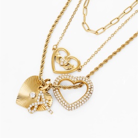 Gold-tone layered necklace set with crystal-pav&eacute; heart pendant, fan charm, and paperclip chain styles