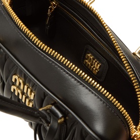 Miu Miu Nero black quilted leather crossbody bag interior, showing gold-tone zip, branded logo plaque and quilted lining detail.