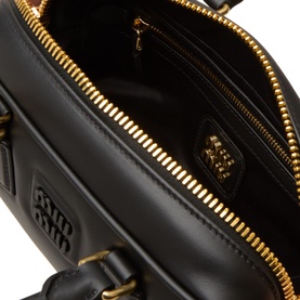 Miu Miu Nero crossbody bag interior, black leather lining, gold-tone zip and embossed logo detail visible inside