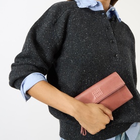 Model carrying Miu Miu Vitello Shine Mini Crossbody Bag in Antico, silver-tone hardware, logo lettering, styled with dark speckled knit and blue