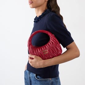 Model carrying Miu Miu Wander Matelass&eacute; Crossbody Bag in Rosso with gold-tone hardware and quilted leather finish, styled with navy top and jeans