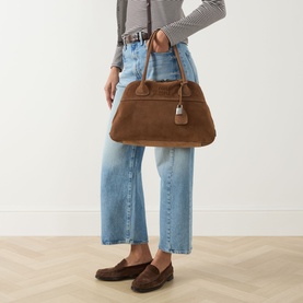 Model carrying Miu Miu Vivant Medium Suede Tote Bag in Cacao with gold-tone hardware and lock charm, styled with jeans and loafers