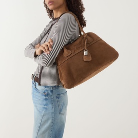 Model carrying Miu Miu Vivant Medium Suede Tote Bag in Cacao with gold-tone hardware and lock detail, styled with striped top and jeans