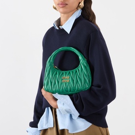 Model carrying Miu Miu Wander Matelass&eacute; Crossbody Bag in Mango green leather with gold-tone hardware, styled with navy sweater.