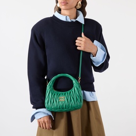 Model carrying Miu Miu Wander Matelass&eacute; Crossbody Bag in Mango green, gold-tone hardware, top handle, worn on shoulder with adjustable strap