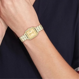 Model with Tommy Hilfiger gold-tone square-dial watch on link bracelet strap, worn on wrist