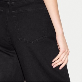 Model wearing Jigsaw black jeans, close-up of rear pocket detail showing wide-leg silhouette