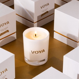 Voya Sea Salt & Cypress Luxury Scented Candle 160g in white glass vessel with gold logo, surrounded by white gift boxes on gold surface