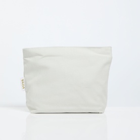 Voya cream canvas wash bag with gold branded label, structured pouch shape with rolled top edge