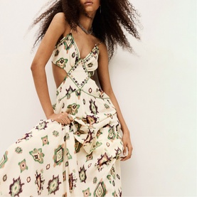 Model wearing Bash cream halterneck midi dress with geometric folk print, cut-out waist detail, and tiered skirt