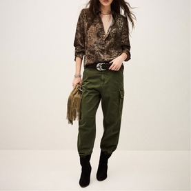 Model wearing Bash green cargo trousers with leopard print shirt, black ankle boots, and carrying a khaki fringe bag