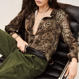 Model wearing Bash green leopard-print shirt, styled with olive cargo trousers, layered necklaces and a black woven clutch bag