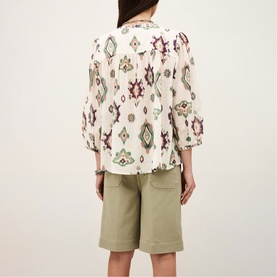 Model wearing Bash cream ikat-print blouse with balloon sleeves, styled with khaki green shorts, seen from behind.