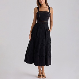 Model wearing House of CB black midi dress with square neckline, broderie anglaise skirt, sheer waist panel and tie straps, styled with tan sandals.