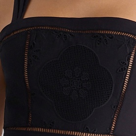 Model wearing House of CB black top with floral broderie anglaise panel and ladder-stitch trim detailing