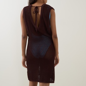 Model wearing Bond Eye walnut crochet dress, rear view showing open back with tie detail and semi-sheer knit skirt