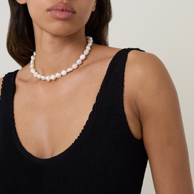 Model with white baroque pearl beaded necklace, styled with black textured swimsuit