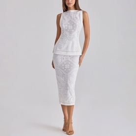 Model wearing House of CB white lace sleeveless peplum top and matching midi pencil skirt, styled with nude heeled sandals