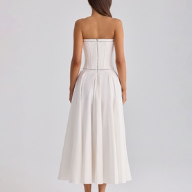Model wearing House of CB white strapless midi dress with structured corset bodice and full pleated skirt, seen from behind