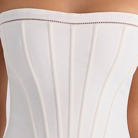Model wearing House of CB white strapless corset top with vertical boning detail and contrast stitch trim at neckline.