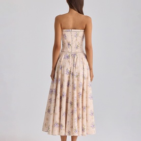 Model wearing House of CB Ivory Sweet Peony strapless midi dress with floral print, pleated skirt, and structured bodice, seen from behind.