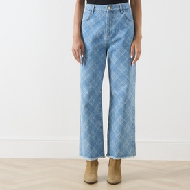 Model wearing Hayley Menzies blue wide-leg jeans with argyle denim print and raw frayed hem, styled with tan ankle boots.
