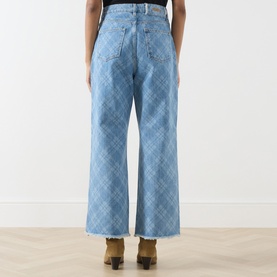 Model wearing Hayley Menzies blue wide-leg jeans with diamond pattern stitching, raw hem, rear view, styled with tan boots.