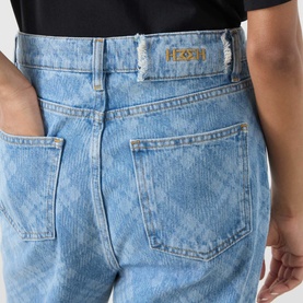 Model wearing Hayley Menzies blue cotton jeans with allover diamond jacquard pattern, gold logo tab, and frayed waistband detail.