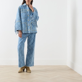Model wearing Hayley Menzies blue denim jacket with stud trim and fringe sleeves, styled with matching wide-leg trousers and tan ankle boots