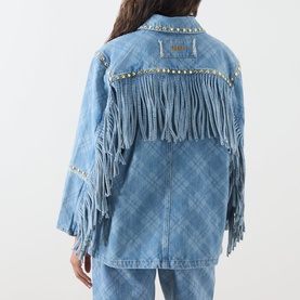 Model wearing Hayley Menzies blue denim jacket, back view, with fringe panels, gold stud trim, and tonal blue jeans.