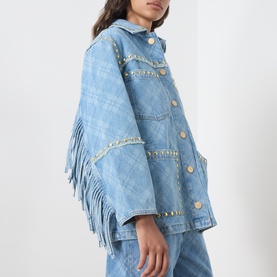 Model wearing Hayley Menzies blue denim jacket with fringe trim, gold stud embellishments, and button front, styled with matching denim trousers