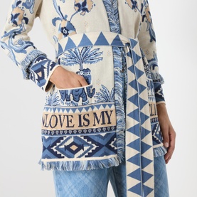Model wearing Hayley Menzies Nandita Jacquard Wrap Cardigan in blue with elephant and palm tree print, fringe trim, and patch pockets, styled with