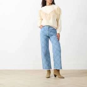 Model wearing Hayley Menzies Sabina Fringe Sweatshirt in Ecru with faux-suede fringing, styled with light blue check wide-leg jeans and tan ankle