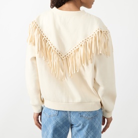 Model wearing Hayley Menzies Sabina Fringe Sweatshirt in Ecru, showing back with chevron faux-suede fringing and gold eyelets, styled with blue jeans