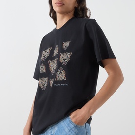 Model wearing Hayley Menzies black cotton T-shirt with repeated leopard head graphic print in gold and cream, styled with blue jeans