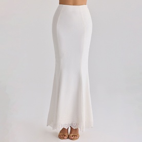 Model wearing House of CB white maxi skirt with fishtail hem and scalloped lace trim, styled with tan heeled mules