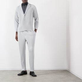 Model wearing Issey Miyake Pleated Single-Breasted Blazer in grey with matching grey pleated trousers and black loafers.