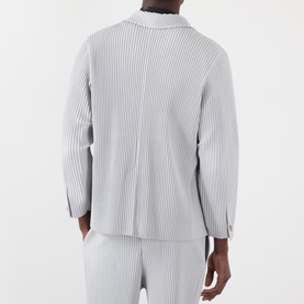 Model wearing Issey Miyake Pleated Single-Breasted Blazer in grey, shown from behind, with matching grey pleated trousers.