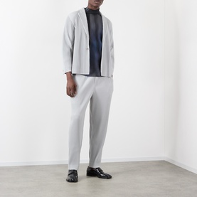 Model wearing Issey Miyake Pleated Single-Breasted Blazer in grey with matching grey trousers, navy turtleneck, and black leather shoes.