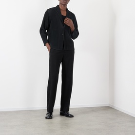 Model wearing Issey Miyake black polyester blazer with matching trousers and black leather loafers.