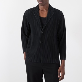 Model wearing Issey Miyake black pleated polyester blazer with notched lapel and two-button front, styled with black trousers.