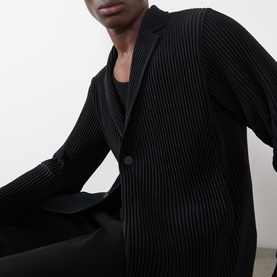 Model wearing Issey Miyake black pleated polyester blazer, styled with matching black trousers and vest top.