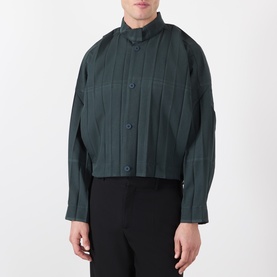 Model wearing Issey Miyake dark green pleated casual shirt with mandarin collar and button front, styled with black trousers