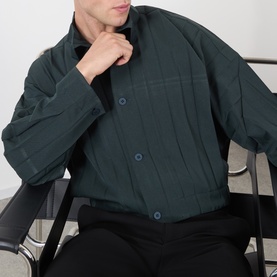 Model wearing Issey Miyake Dark Green casual shirt with textured pleated fabric and navy buttons, styled with black trousers