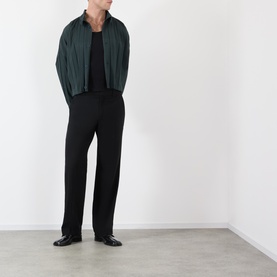 Model wearing Issey Miyake dark green casual shirt jacket, styled with black wide-leg trousers and black loafers.