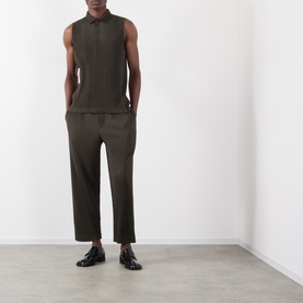 Model wearing Issey Miyake Pleated Wide Leg Trousers in brown with matching sleeveless top and black patent loafers.