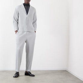 Model wearing Issey Miyake Pleated Wide Leg Trousers in grey, styled with matching grey cardigan and black loafers.
