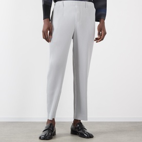 Model wearing Issey Miyake Pleated Wide Leg Trousers in grey with elasticated waist, styled with black patent loafers.